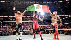 Rey Mysterio, Raquel Rodríguez y AJ Styles sostienen la bandera de México en un House Show.